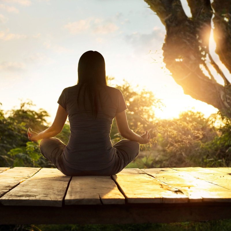 Woman practicing meditation yoga on the nature at sunset